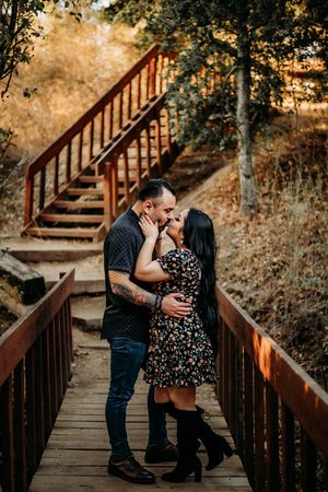 Couple kissing each other on a bridge with a staircase in the background.