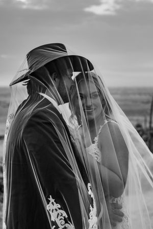Couple snuggled up to each other under a veil.