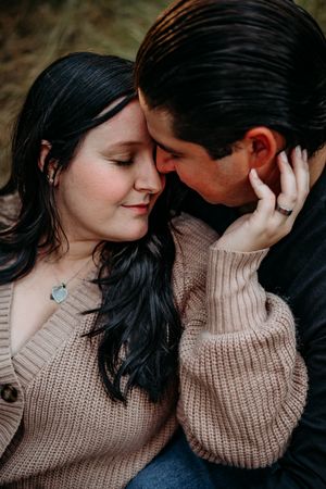 Picture of a couple snuggling forehead to forehead with the female cradling the males face with her hand.