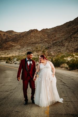 Couple walking in the middle of the road with hills in the background.