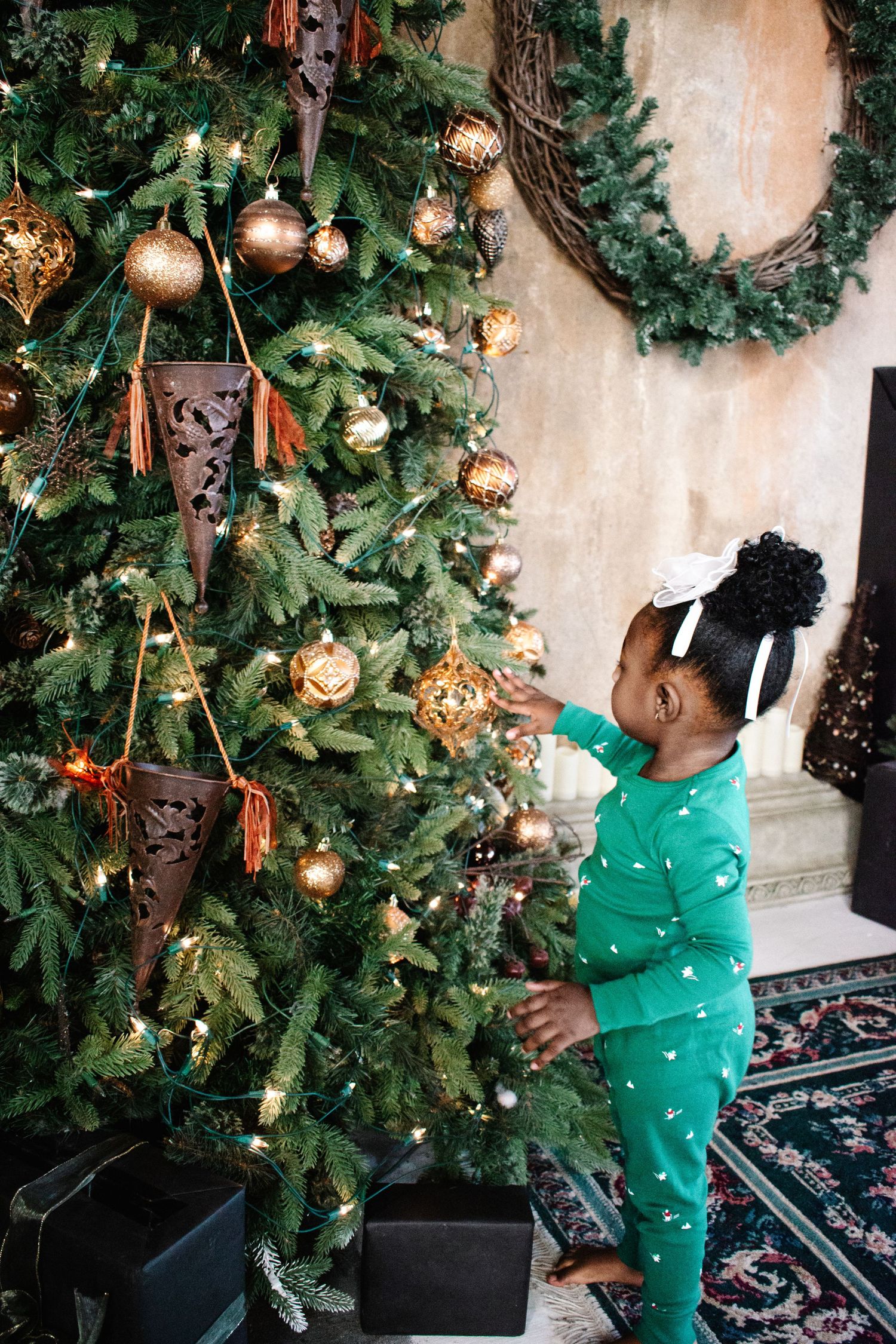 Child decorating Christmas tree in matching pajamas during Tacoma holiday photo session.