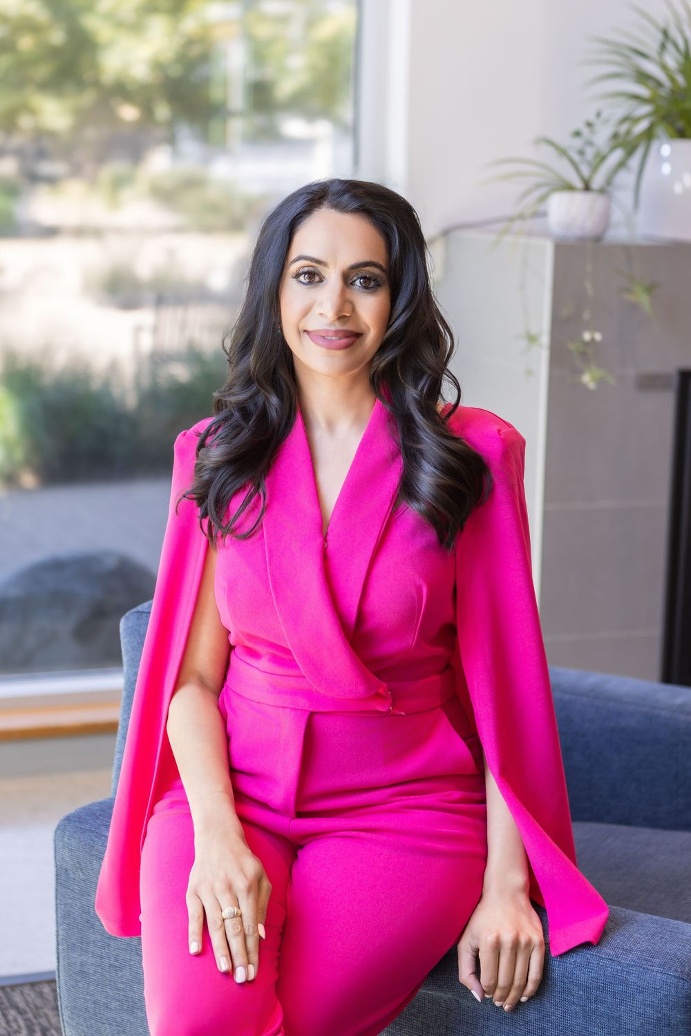 A series of photos showing someone wearing a vibrant hot pink cape dress while sitting on a blue couch.