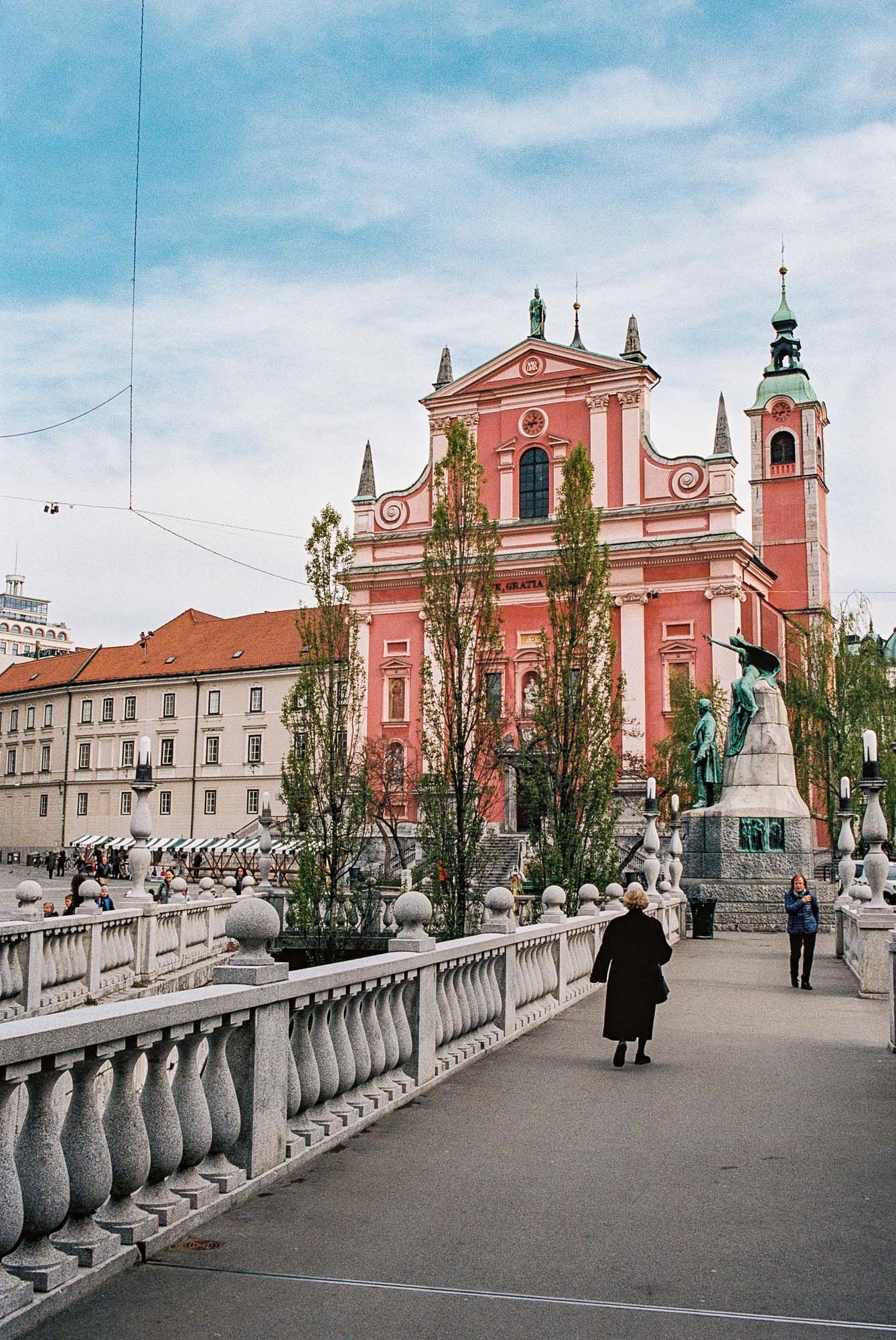 Franciscan Church of the Annunciation with its pink facade and baroque architecture in Ljubljana, Slovenia on a sunny day.
