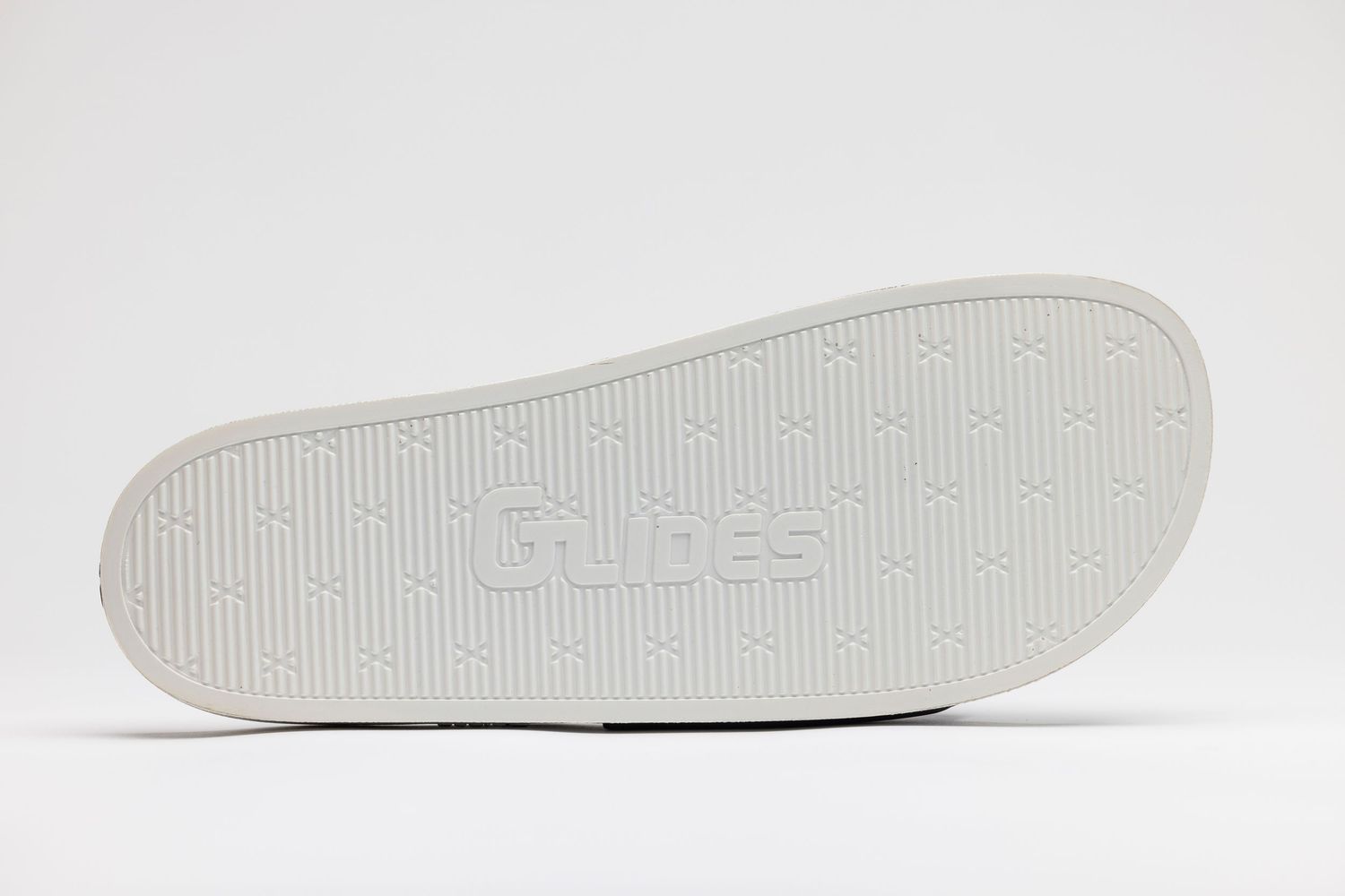 Side view of a white rubber shoe sole with textured grip pattern and branding details.
