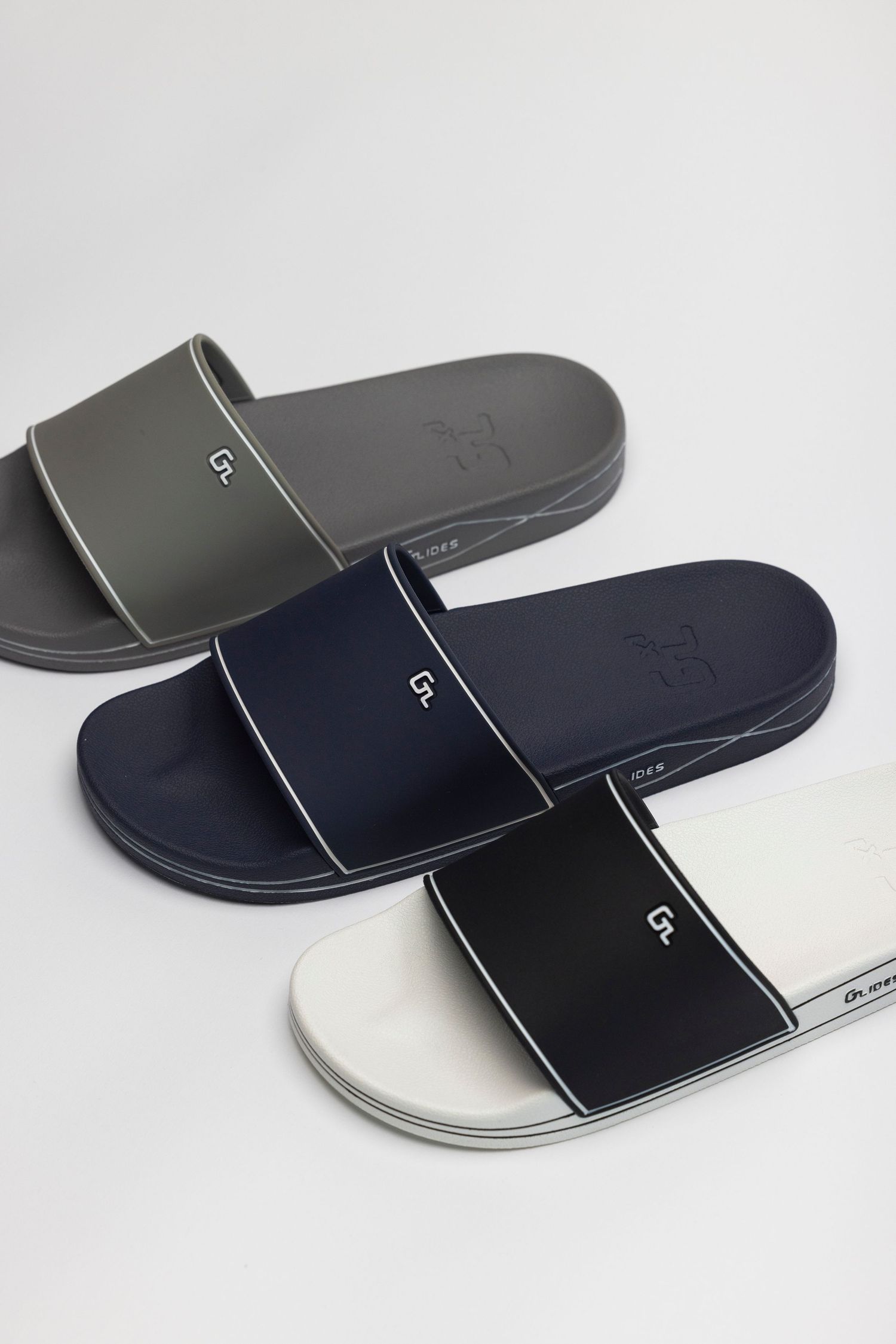 Modern slide sandals in black, navy, and white colorways shown from different angles on white background.