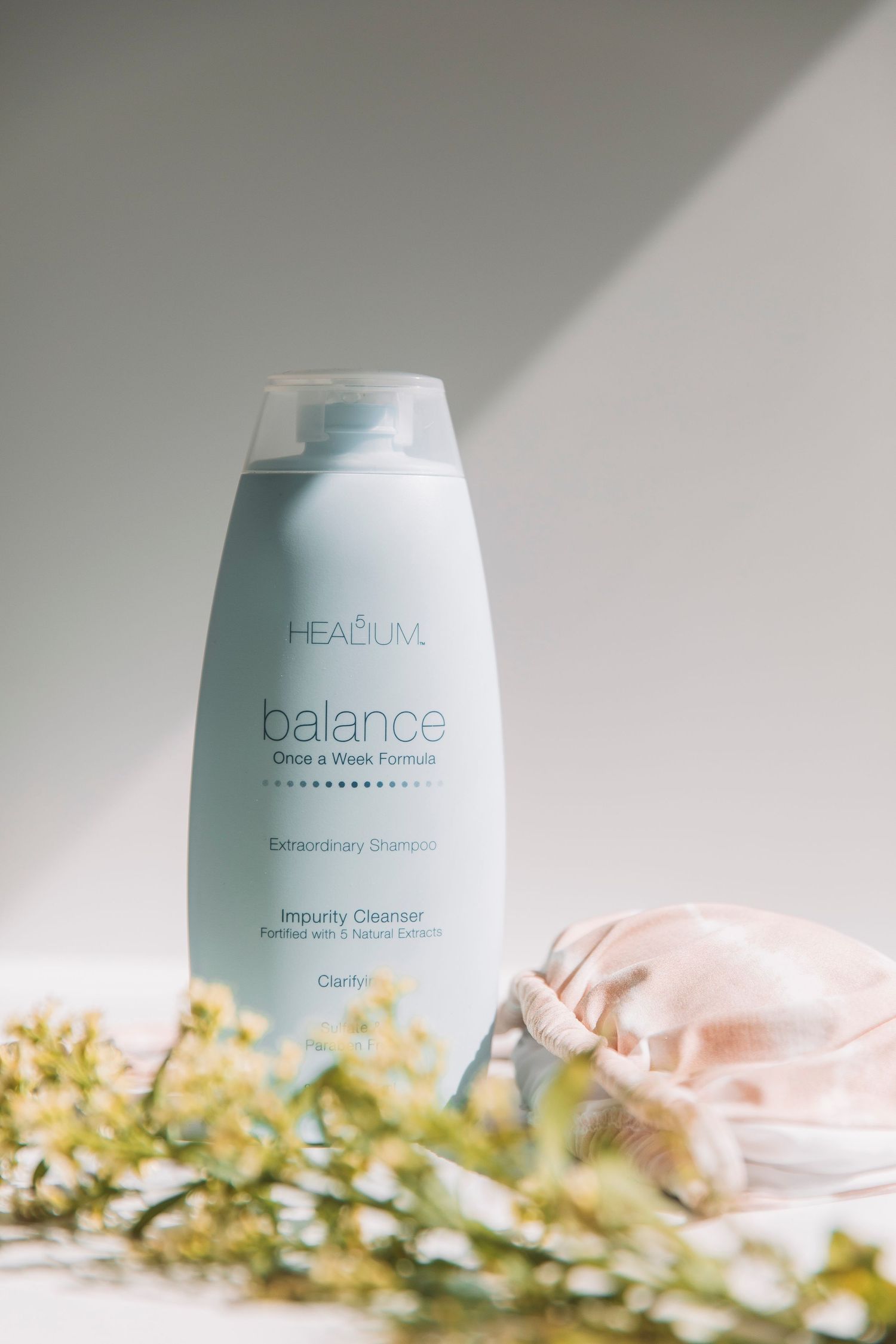 Headium Balance shampoo bottle styled with soft lighting and delicate yellow flowers against neutral background.