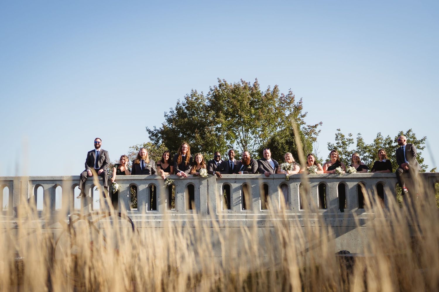 A panoramic view shows a crowd of spectators gathered along a wooden fence watching an outdoor event.