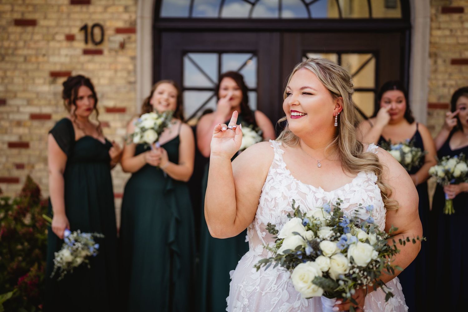 A joyful bride in a white lace dress laughs during an emotional moment at her wedding ceremony.