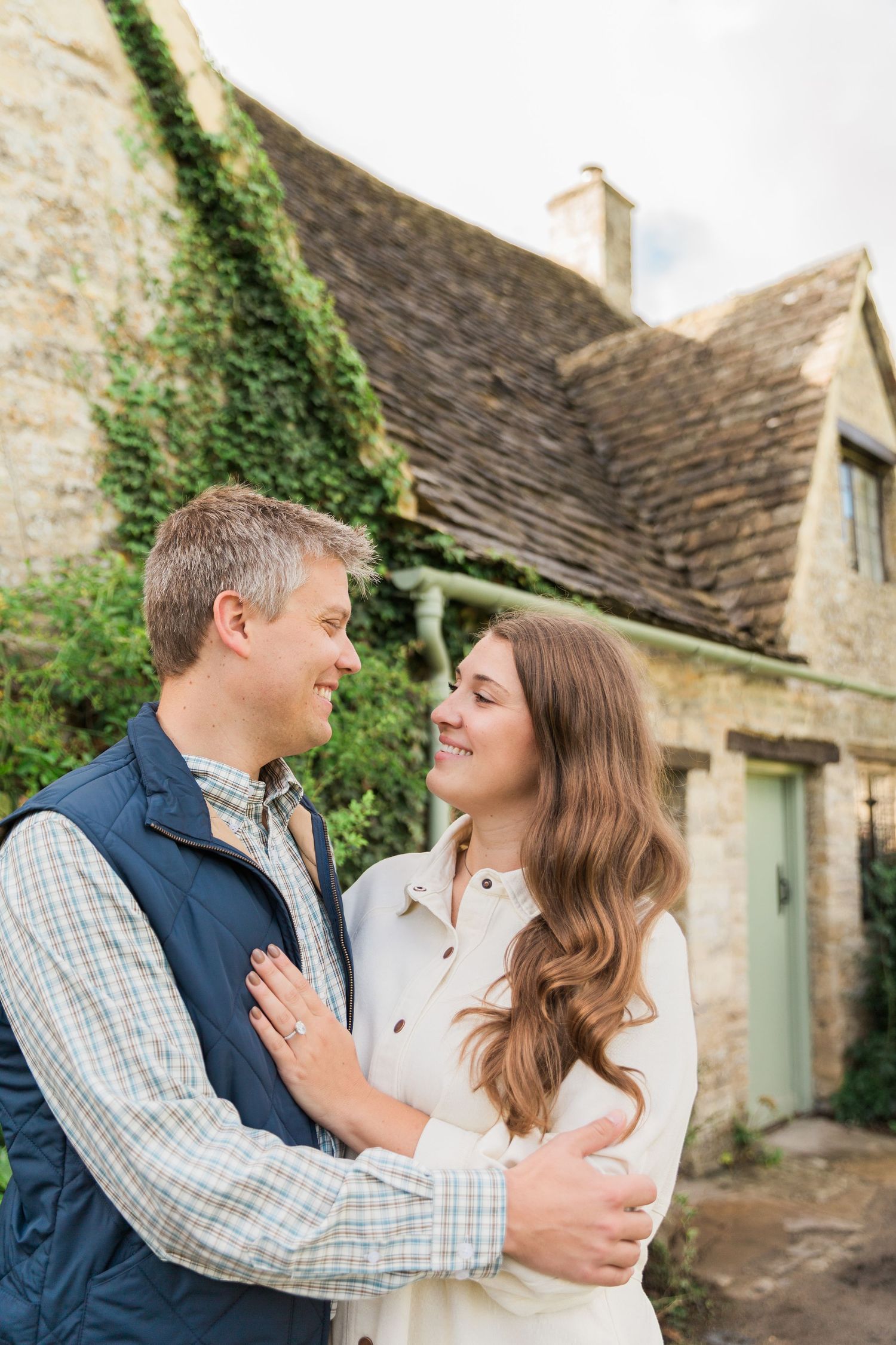 A newly engaged couple embrace in front of Arlington Row Bibury - proposal & engagement photography by Hayley Elizabeth