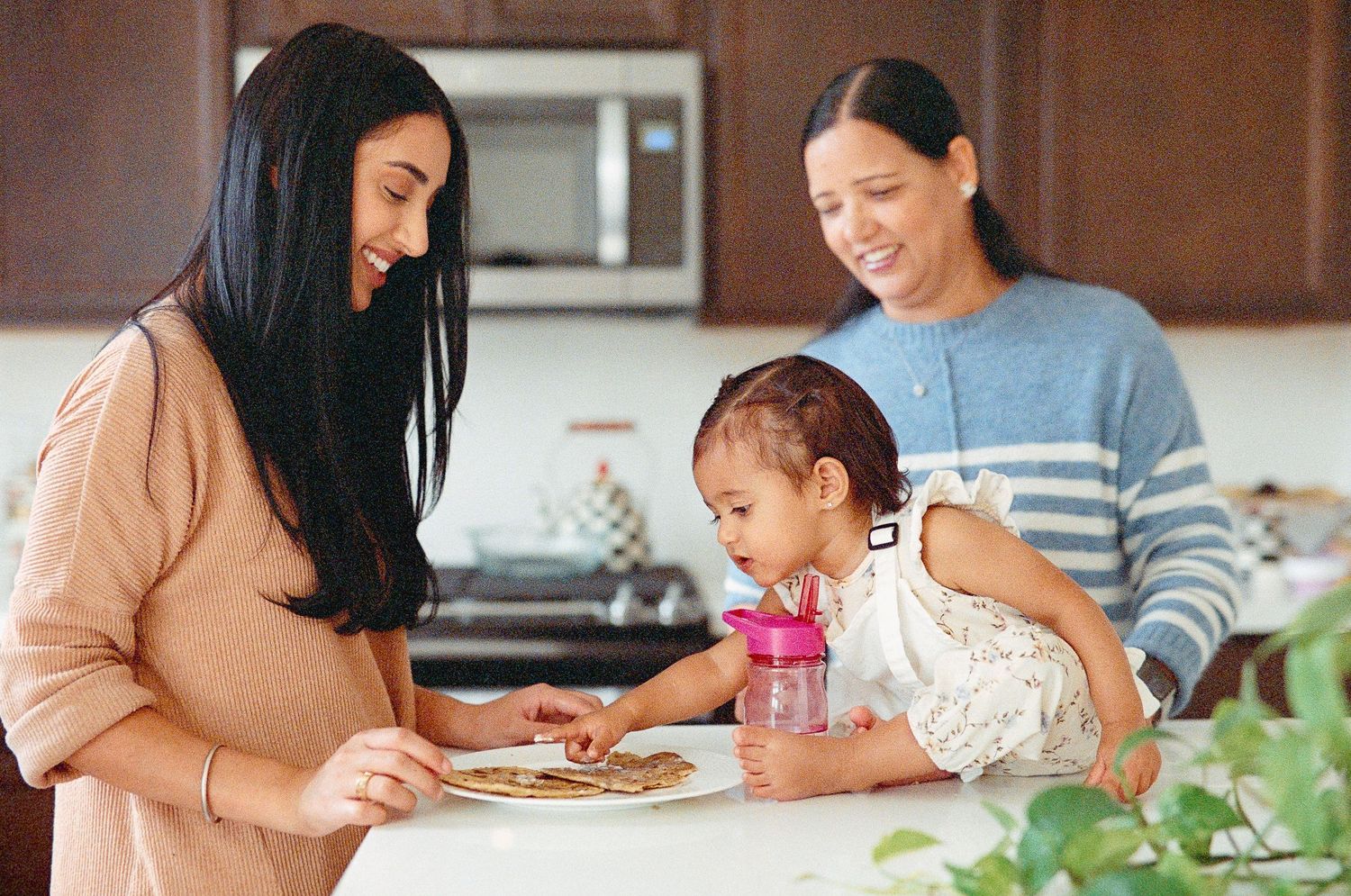 A family enjoys a meal together at a wooden dining table in their kitchen.