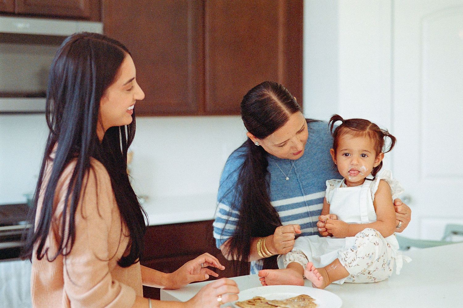 A series of photos showing someone teaching a young child to bake and cook in a modern kitchen.