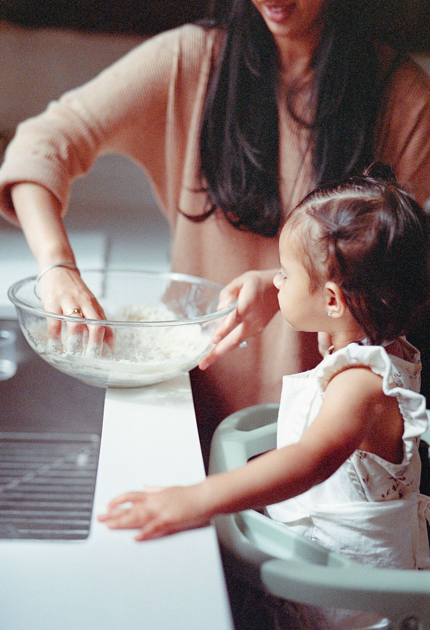 Close-up sequence showing hands mixing ingredients in a glass bowl during a baking process.