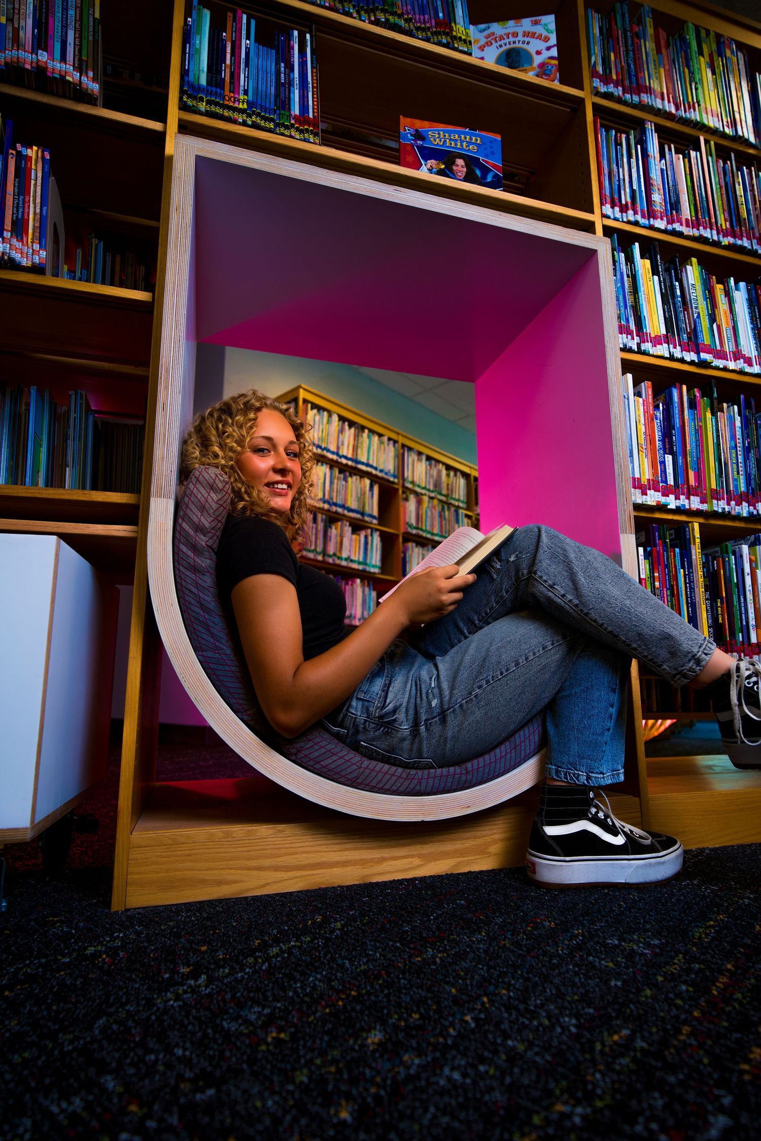 Creative portrait of someone relaxing in a curved reading nook at a library.