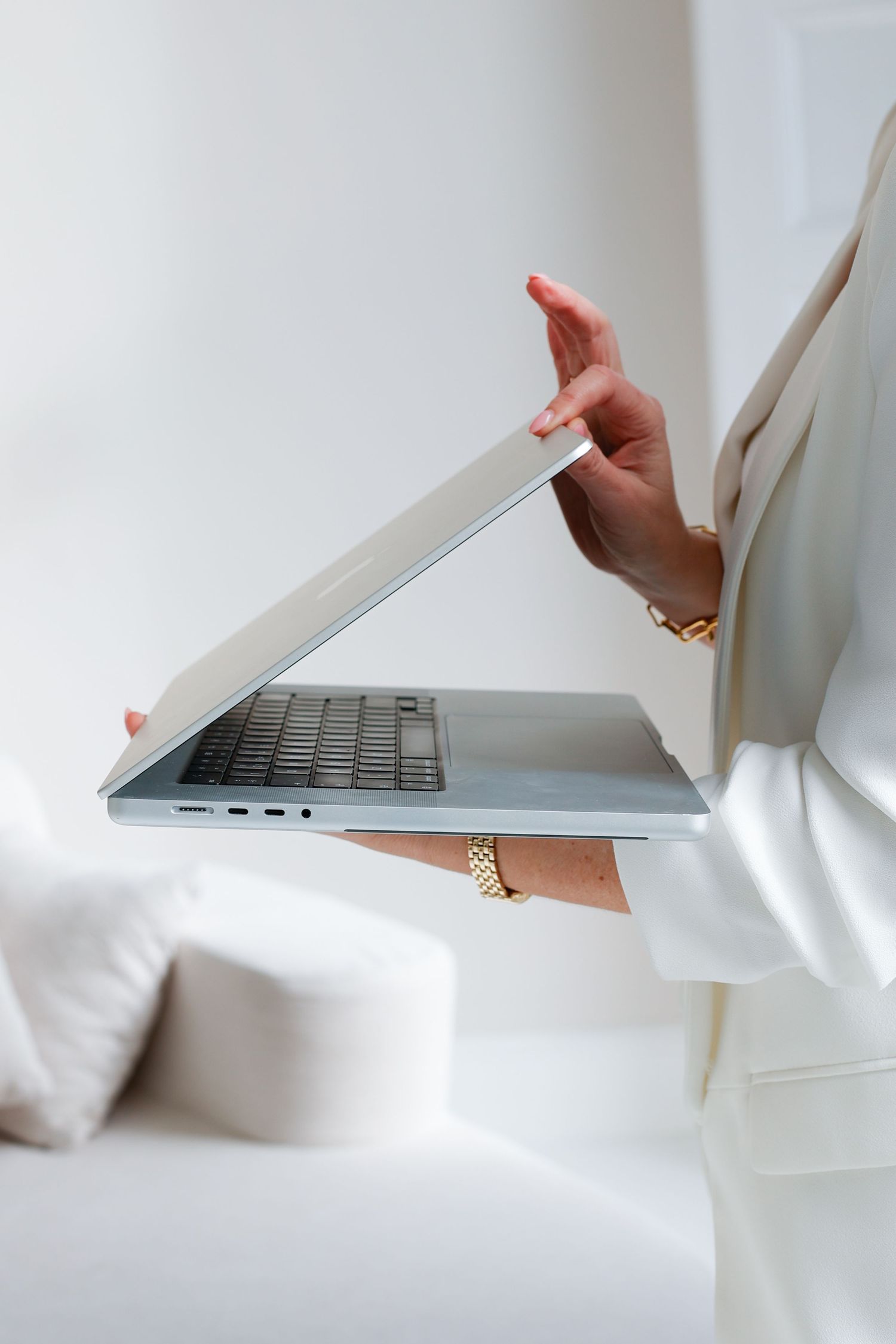 Person sitting on white couch in minimalist white room setting.