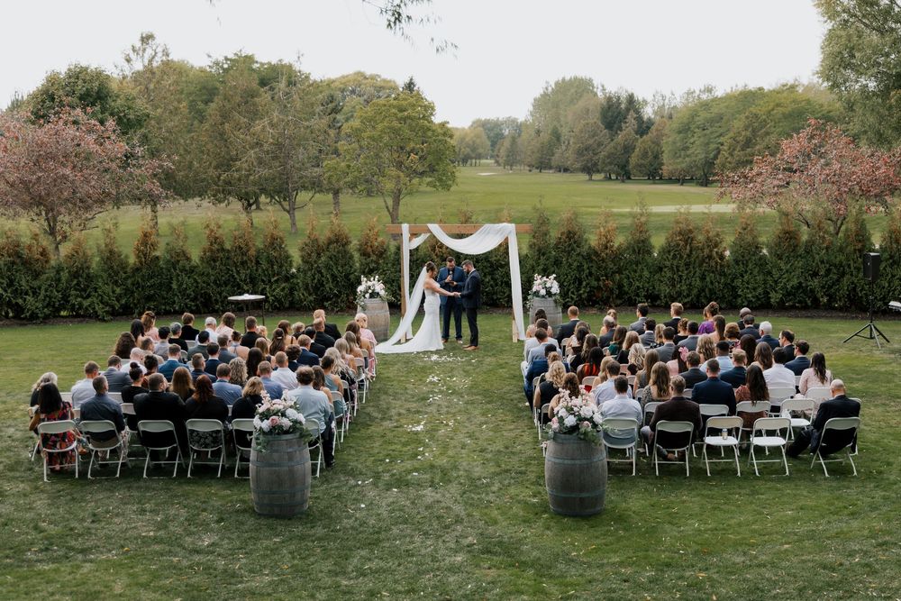 Aerial view of an elegant outdoor wedding ceremony with guests seated on a lush green lawn.