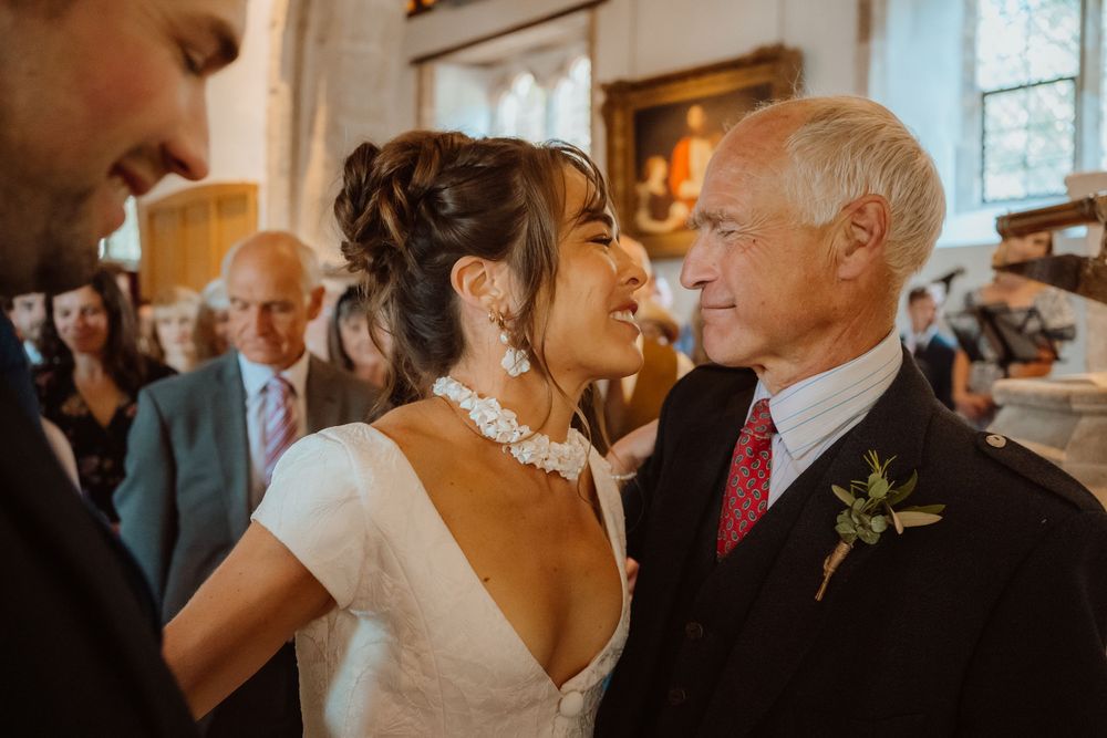A joyful moment captured between two people at a wedding ceremony in a warmly lit indoor venue.