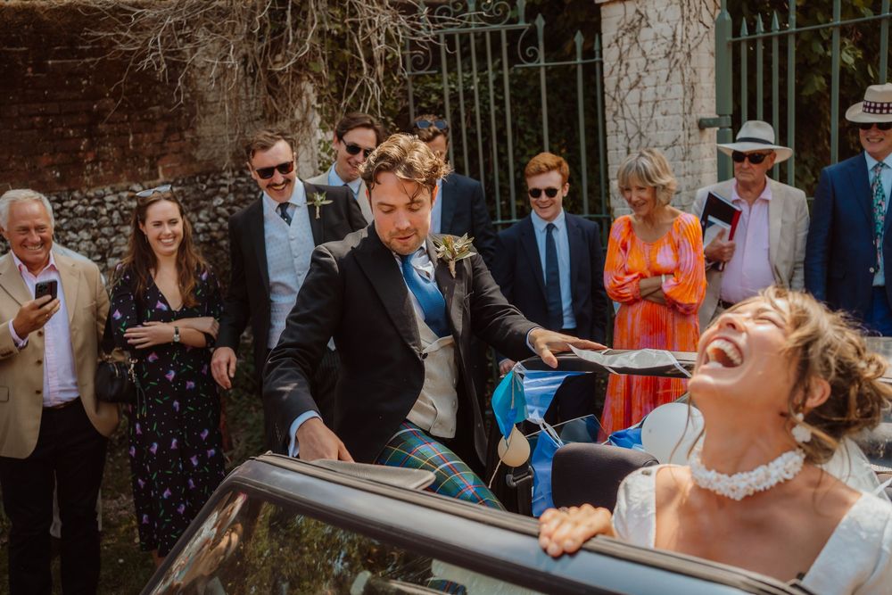 Wedding guests celebrate and laugh while blowing bubbles during an outdoor celebration.