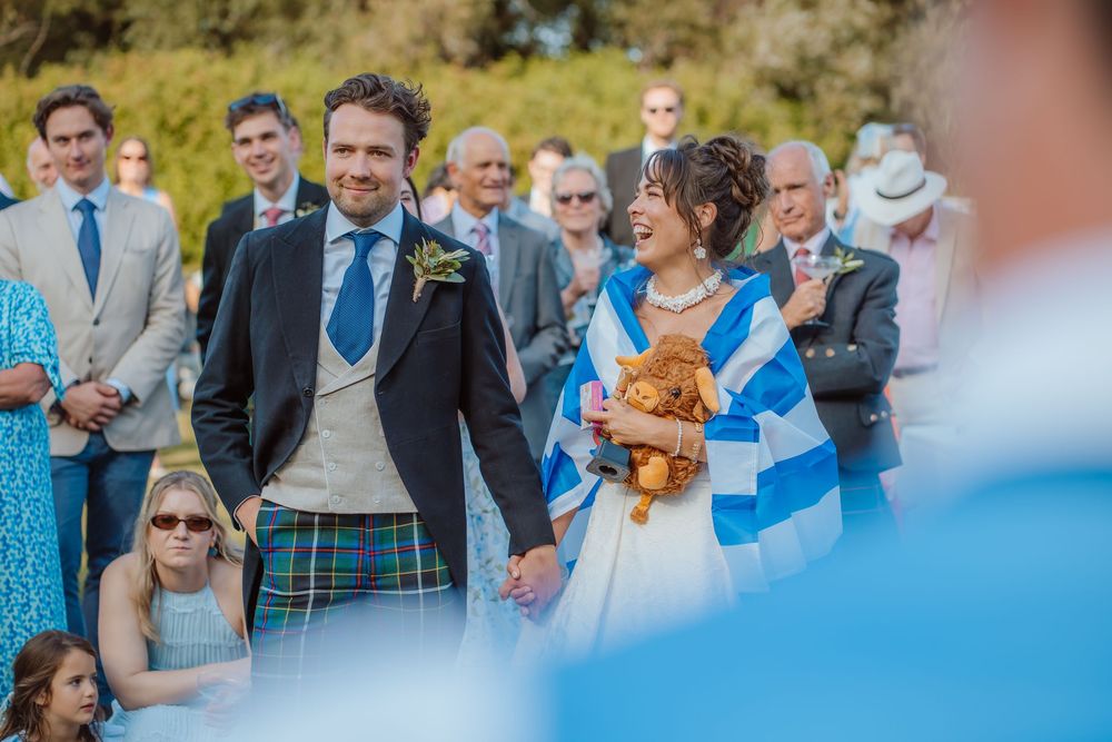 Wedding guests holding up blue pom poms and cheering during an outdoor celebration.