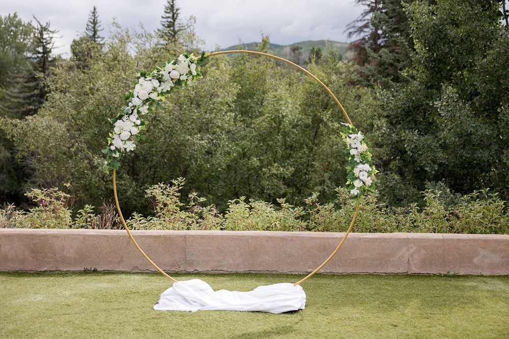 Panoramic view of a grassy outdoor wedding venue with mountains and evergreen trees in the background.