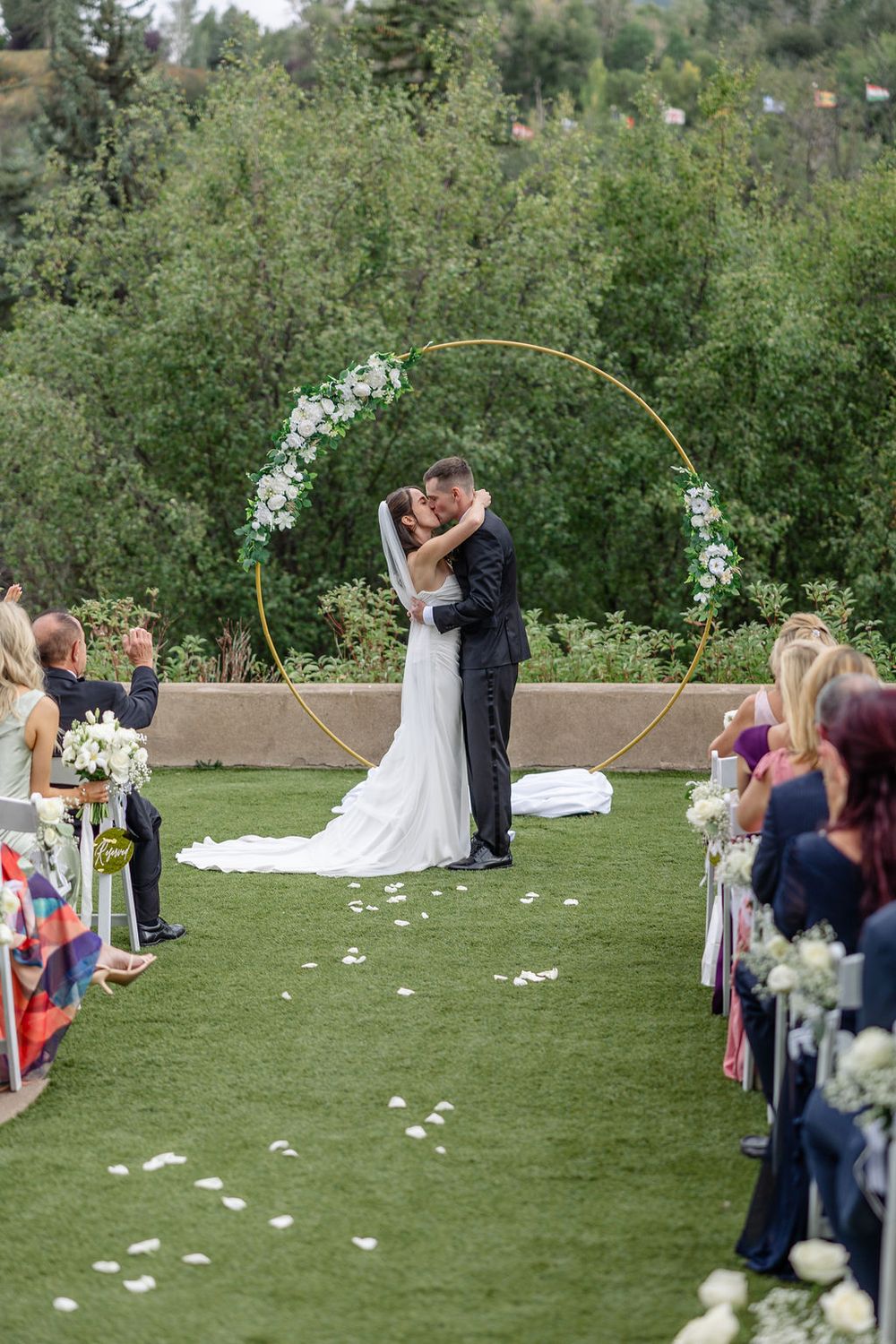 Sequence of wedding ceremony moments captured on a grassy lawn with guests watching from white chairs.