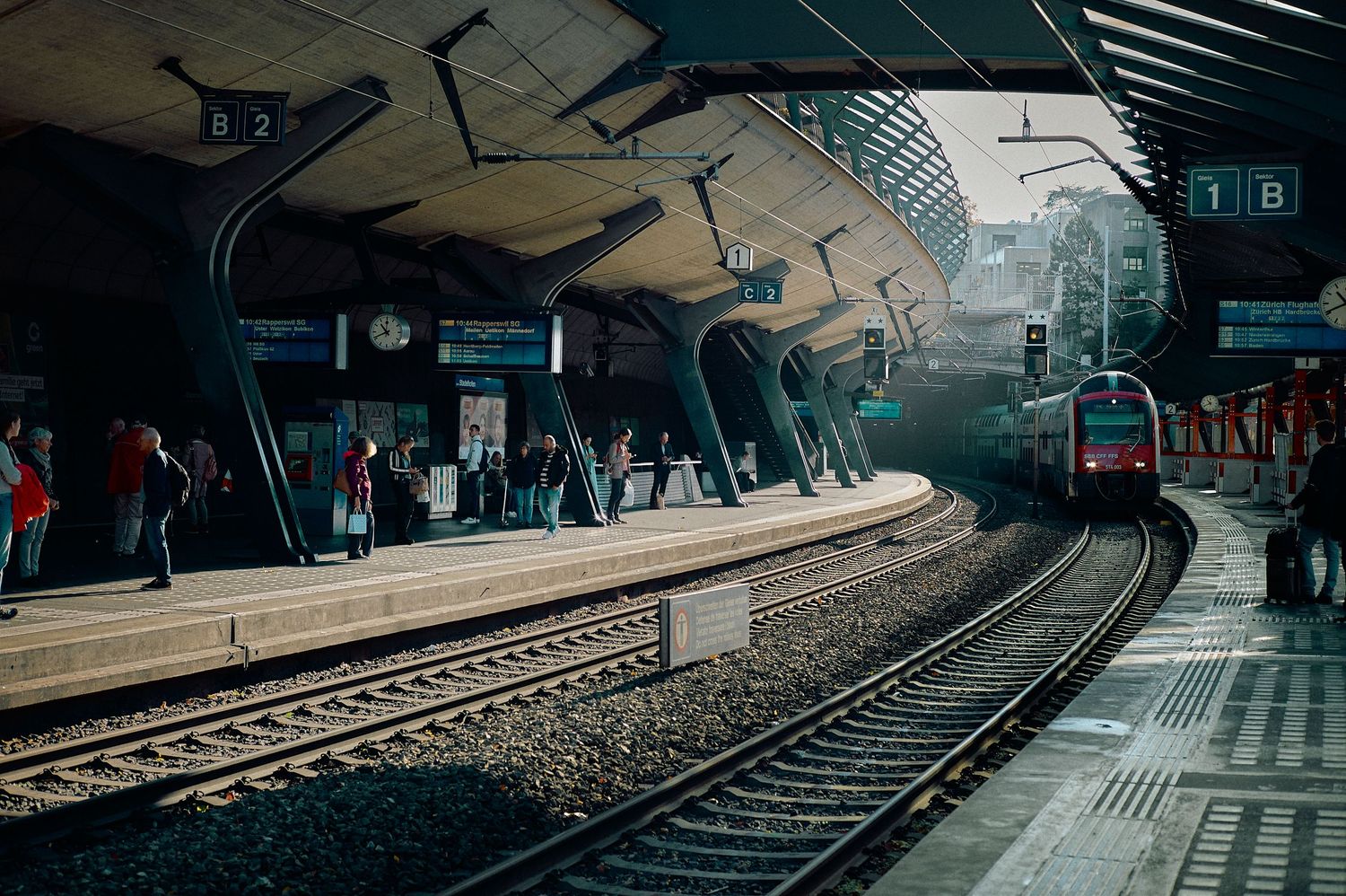 Train tracks curve through a dimly lit underground subway station with dramatic lighting and architecture.