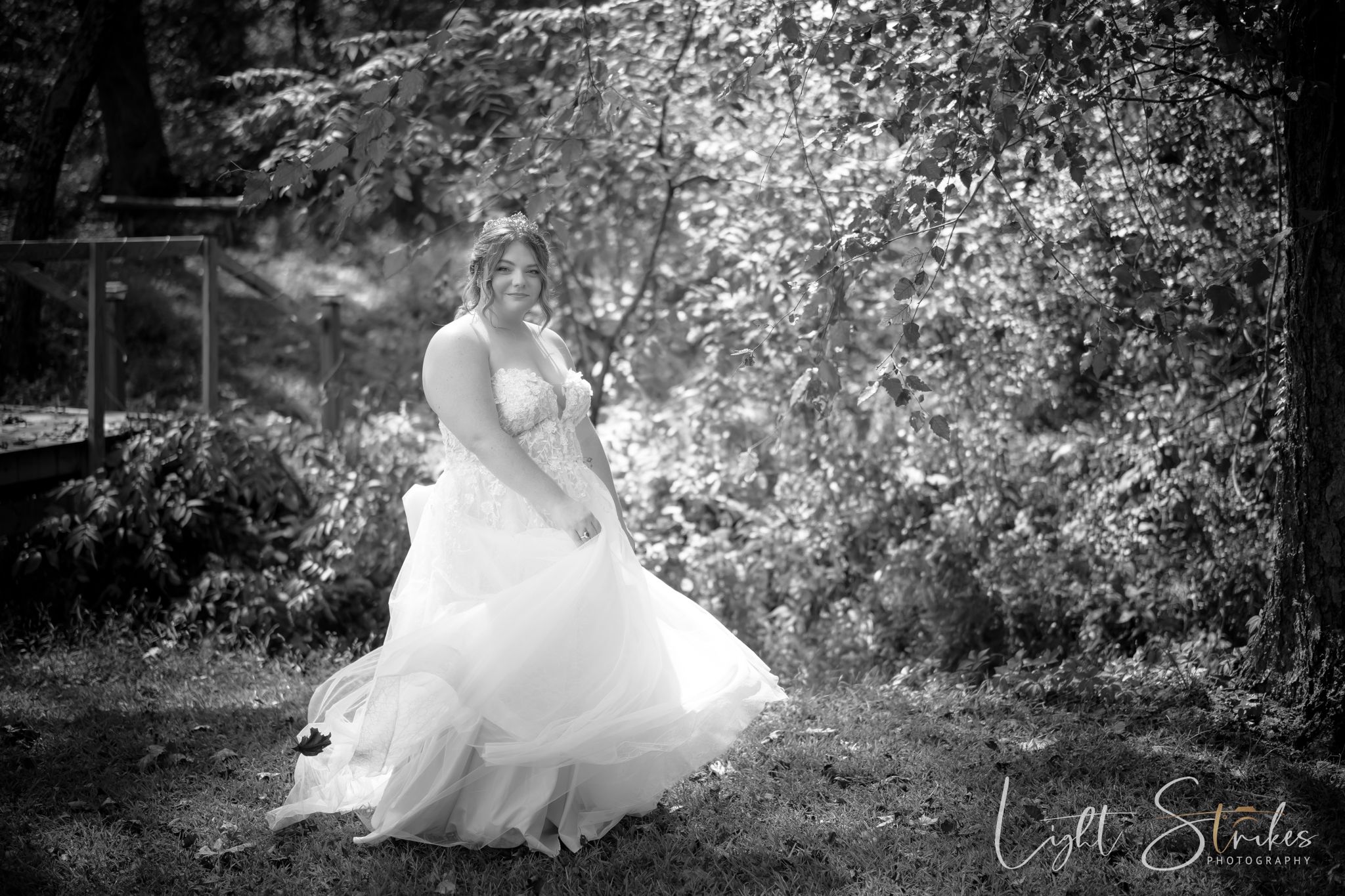 A black and white art wedding photos showing a bride in a flowing white dress walking through a garden setting.