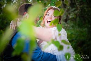 A couple shares a joyful moment together in a lush green garden setting during a wedding photo session.