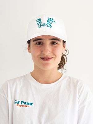 A person wearing a white t-shirt with a company logo smiles warmly against a light background.