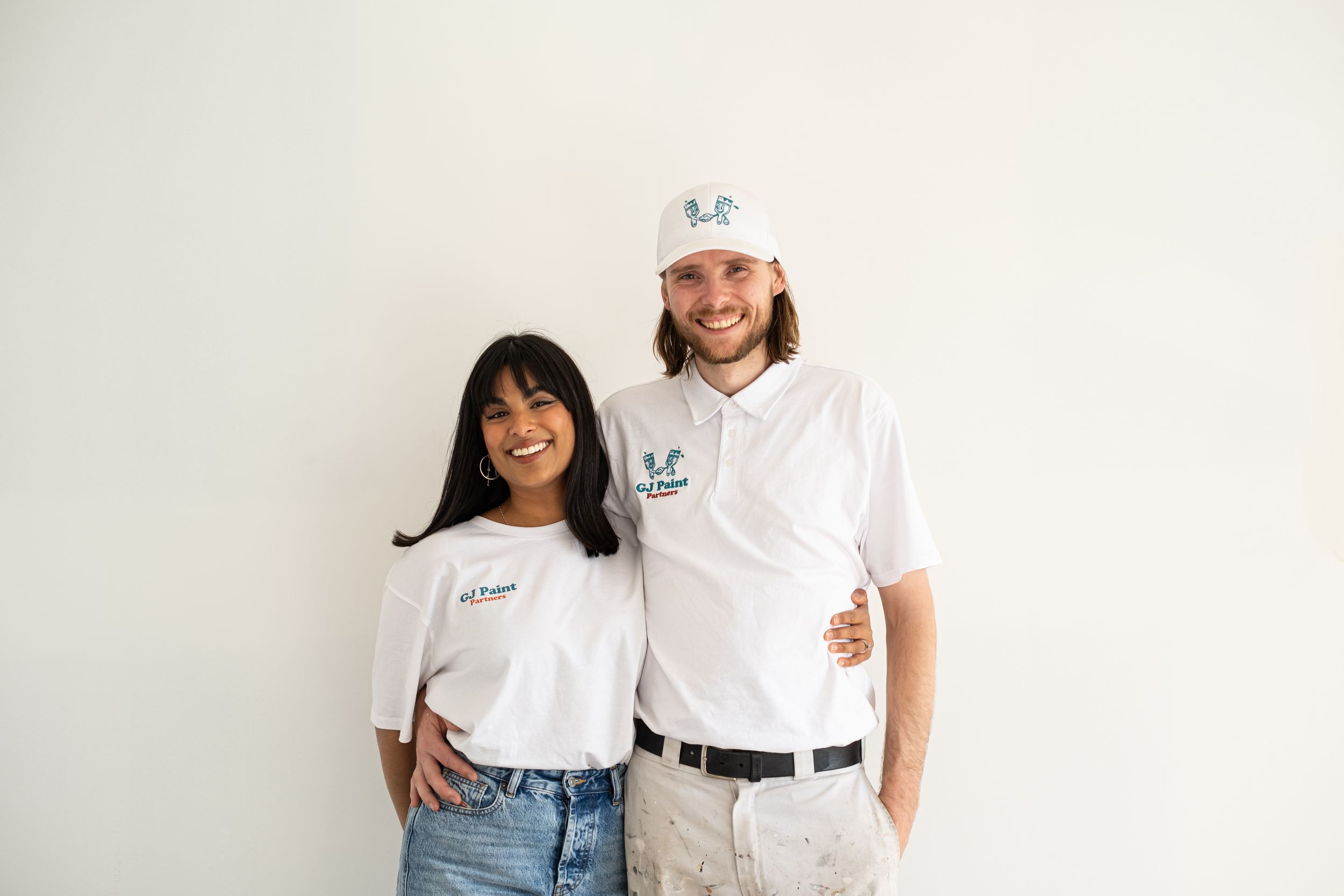 Two people in white t-shirts and jeans pose together against a white background.