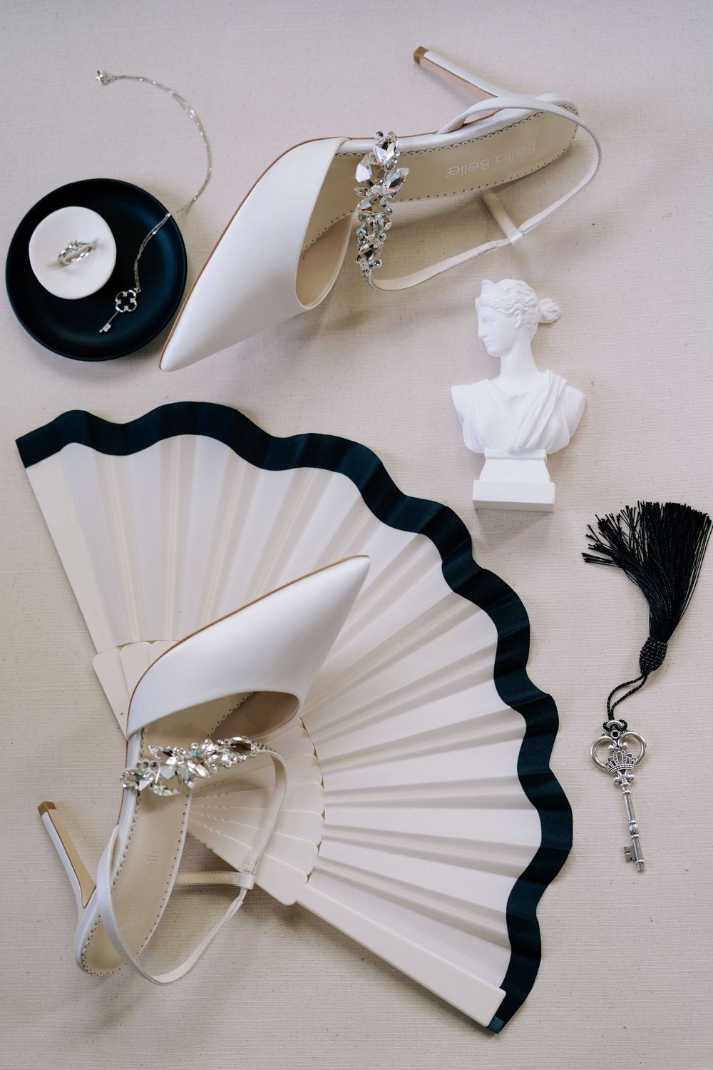 Wedding accessories including fans, jewelry, and delicate white decorative items arranged on beige surface.
