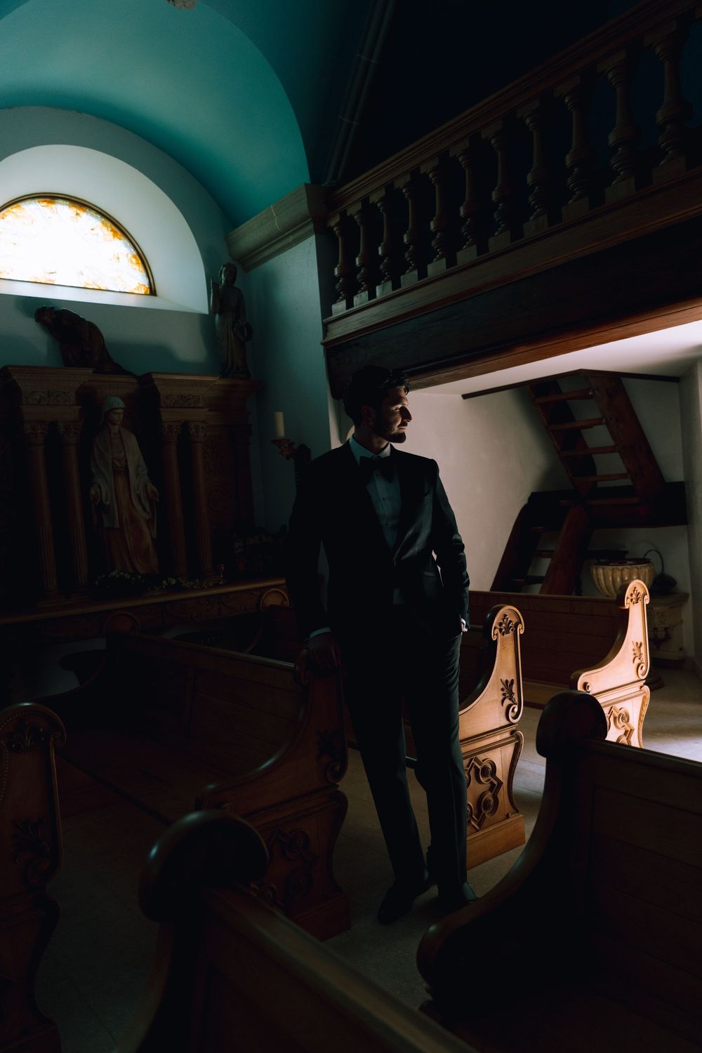 Dark interior hallway with dramatic lighting and ornate wooden balustrades creating moody atmosphere.