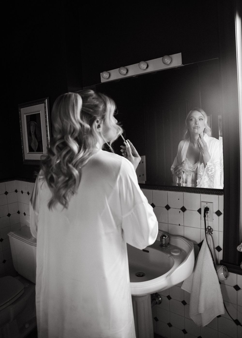 A series of black and white mirror reflections showing someone in a white dress getting ready in a bathroom.