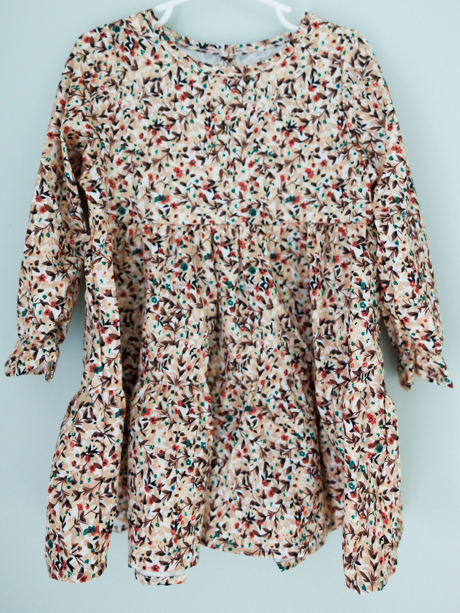 A floral print baby sleeper garment with red and brown pattern shown from multiple angles on a light background.