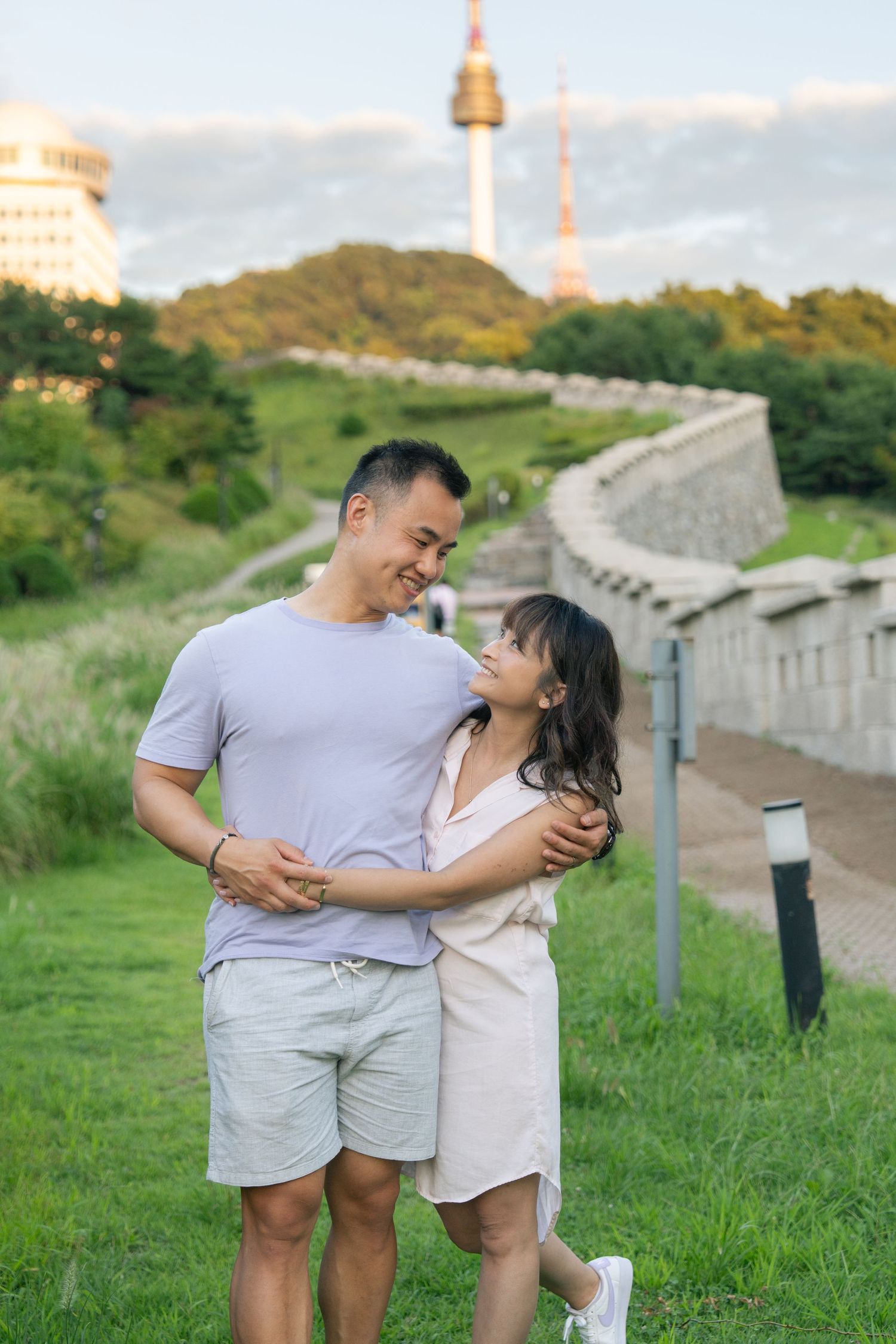 A couple shares a tender moment together while walking along a historic stone wall during sunset.