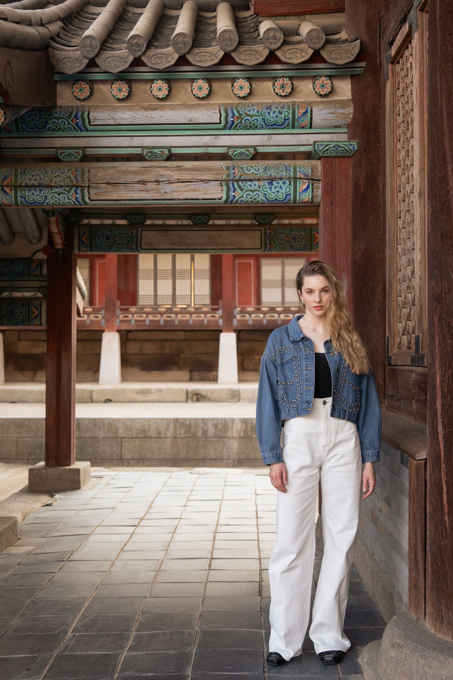 Traditional Korean architecture with ornate wooden columns and tiled roofs at a historic temple or palace courtyard.