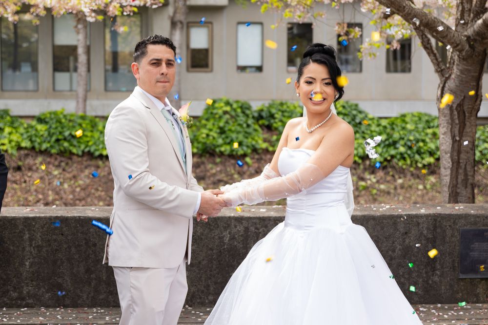 Couple in wedding attire dancing and twirling together on a paved walkway during their celebration.