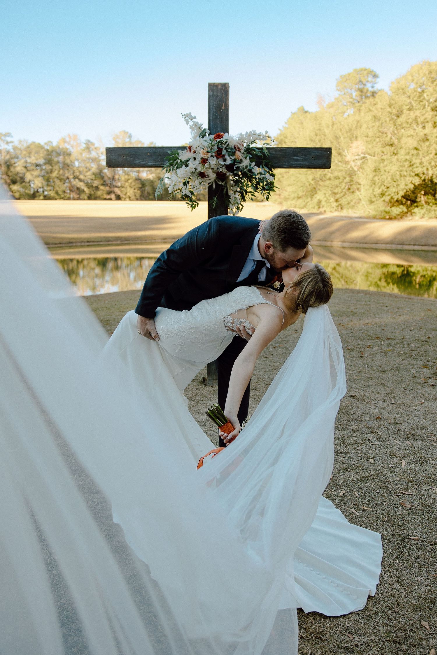 A dramatic dip kiss between newlyweds against a golden sunset backdrop.