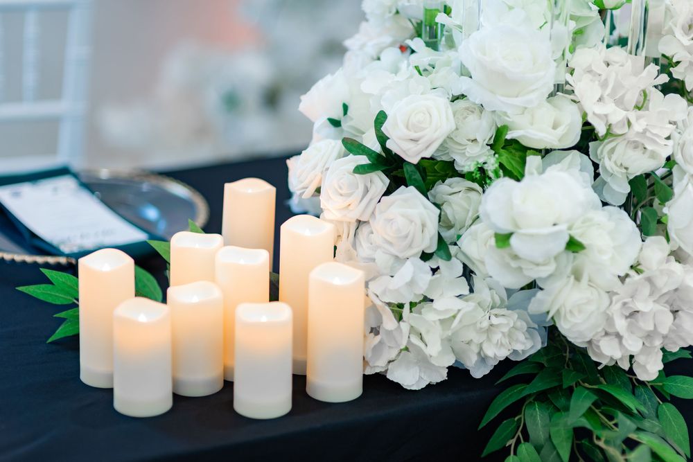 White floral arrangements with glowing candles create an elegant wedding reception table centerpiece.