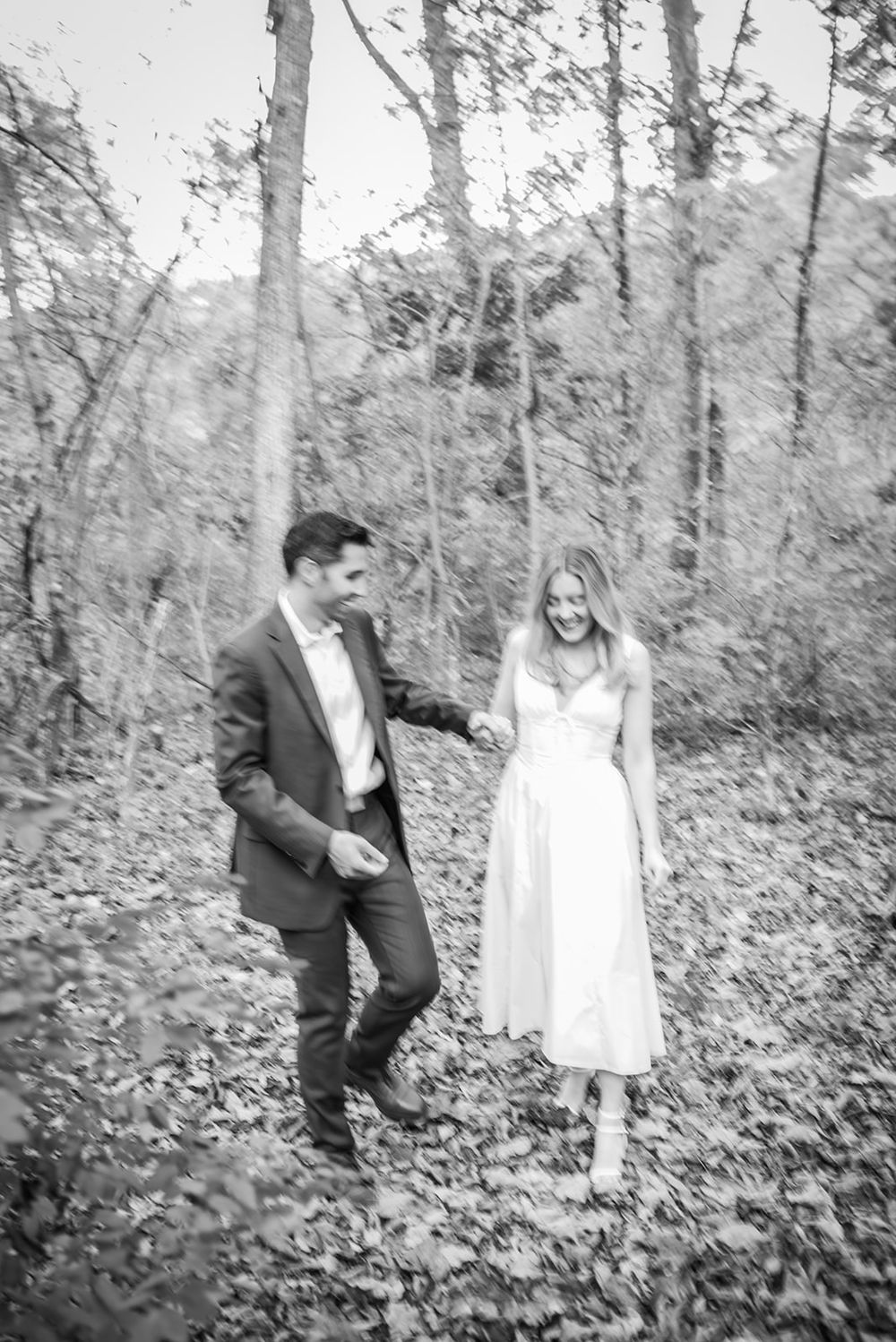 Black and white photo series of a couple playing and running through a wooded area covered in fallen leaves.