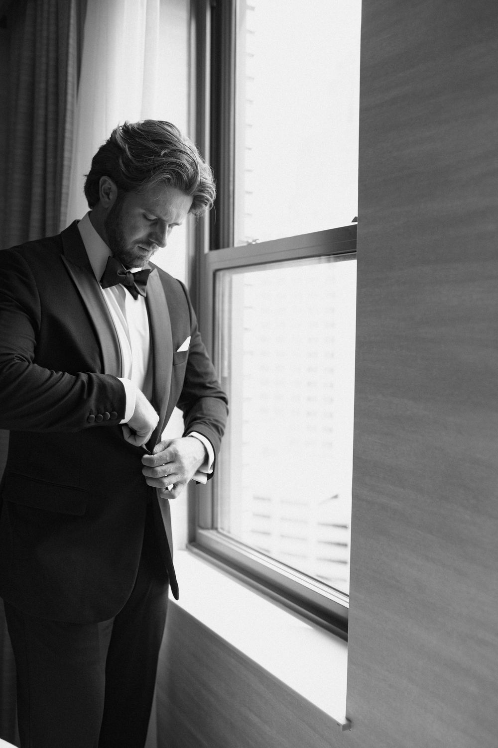 A series of black and white photos showing a person in a suit looking thoughtfully out of a bright window.