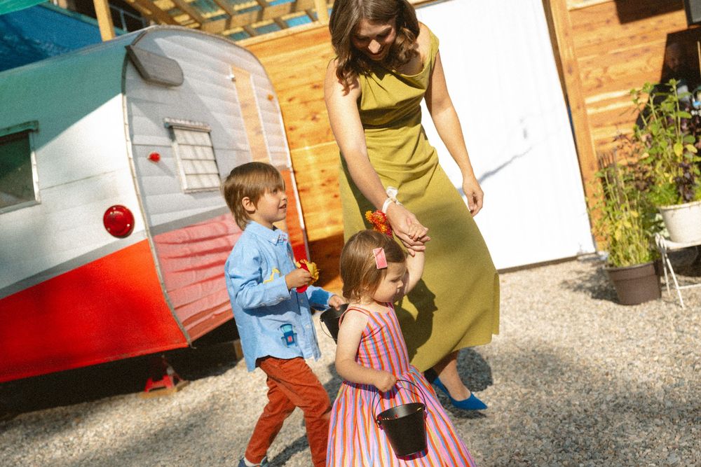Children play and run around a food truck or trailer parked outside on a sunny day.