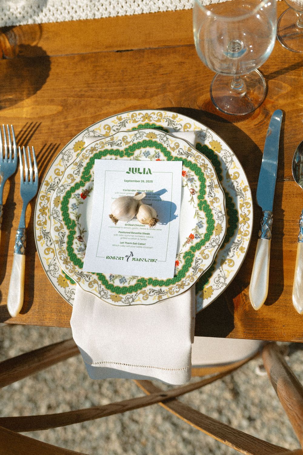 Elegant place settings with floral patterned plates and menus arranged on a rustic wooden table at a formal dinner.