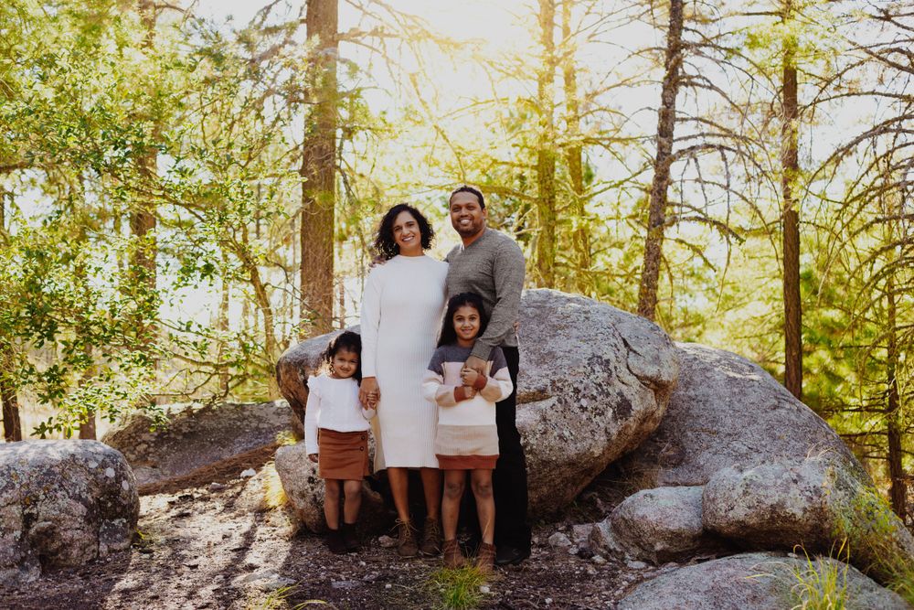 Couples portrait session on large rocks in a sun-dappled forest setting.