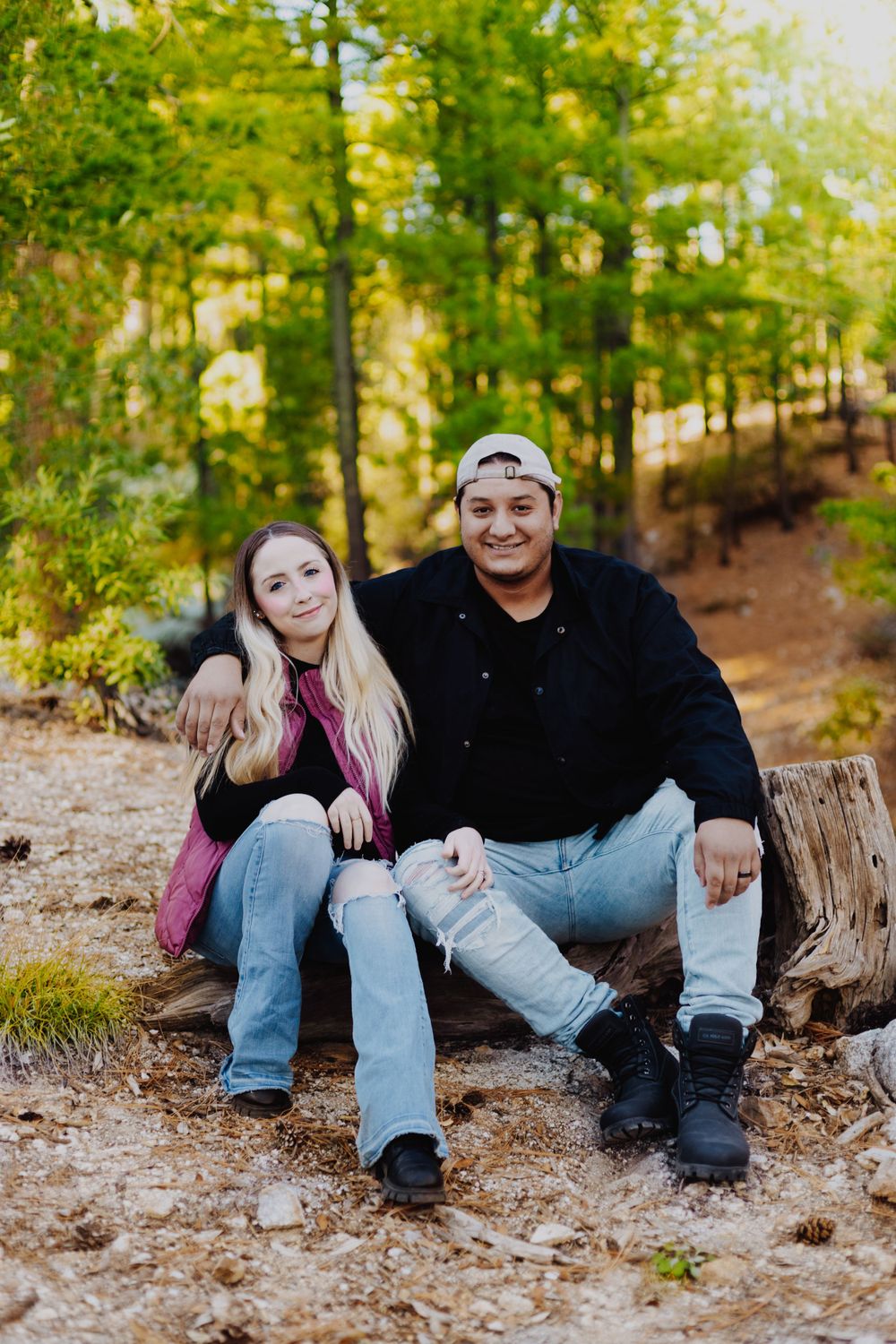 Casual outdoor couples photoshoot on fallen logs in a wooded setting.