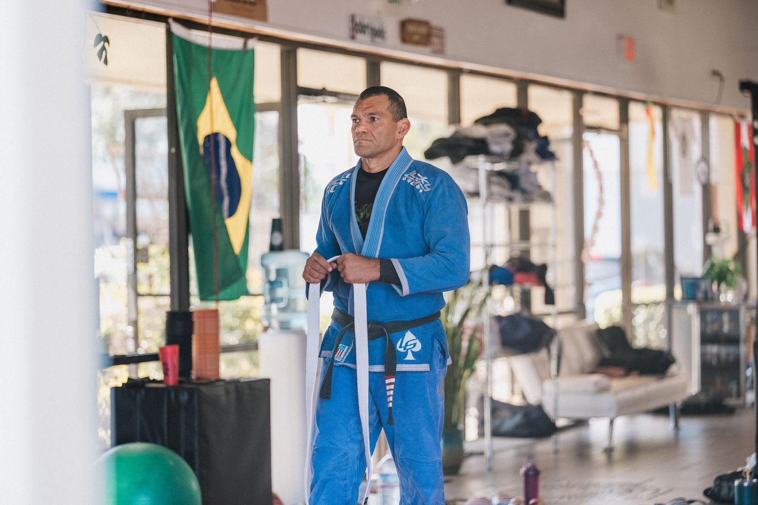 A person in a blue jacket stands in a hallway with flags and display cases visible in the background.