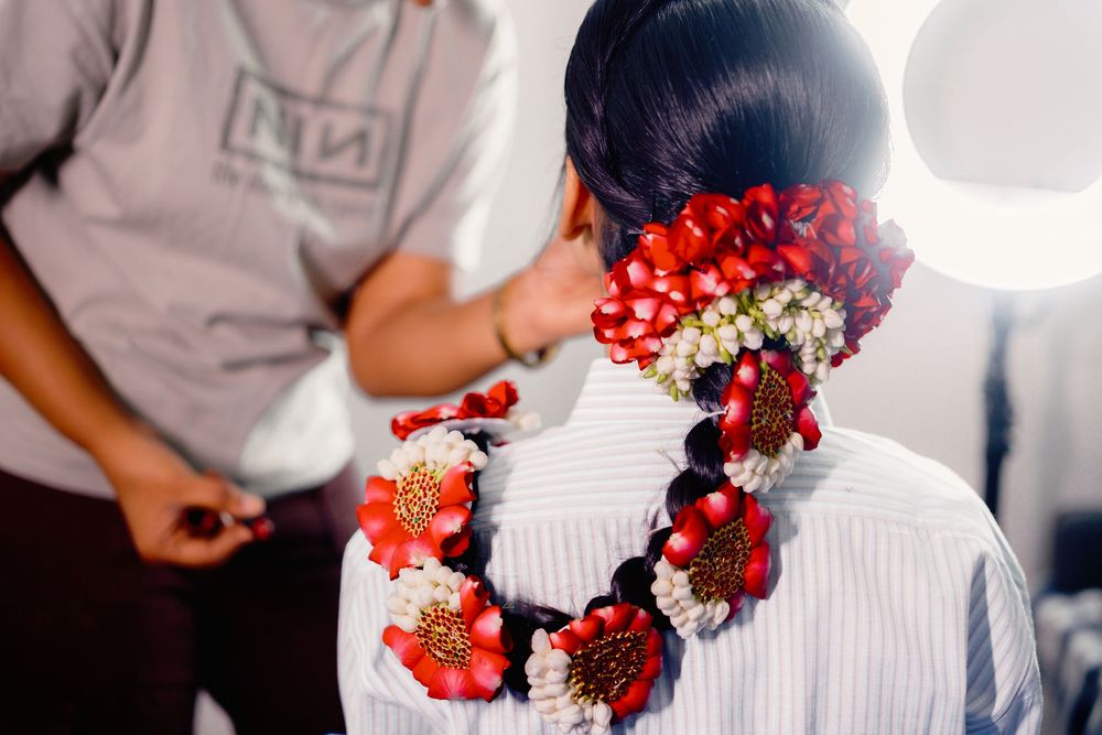 A pair holds vibrant red and burgundy wedding bouquets while wearing traditional Filipino formal attire.