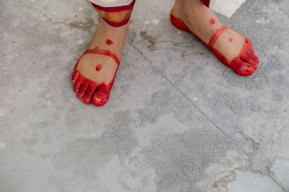 A sequence of red painted footprints walking across a gray concrete floor.