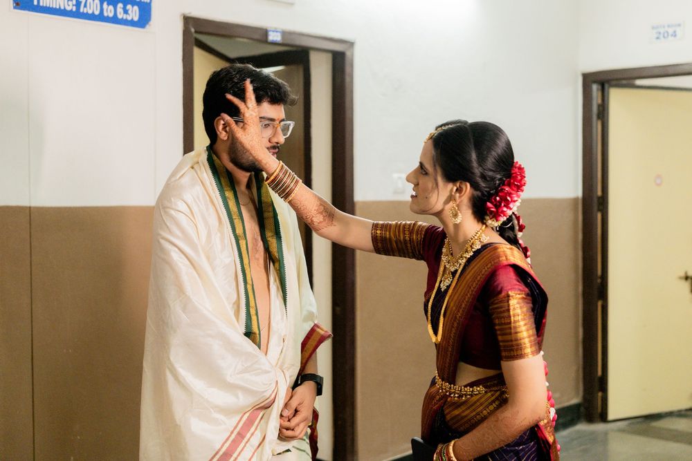 A couple in traditional Indian attire share a candid moment in a hallway during a wedding ceremony.