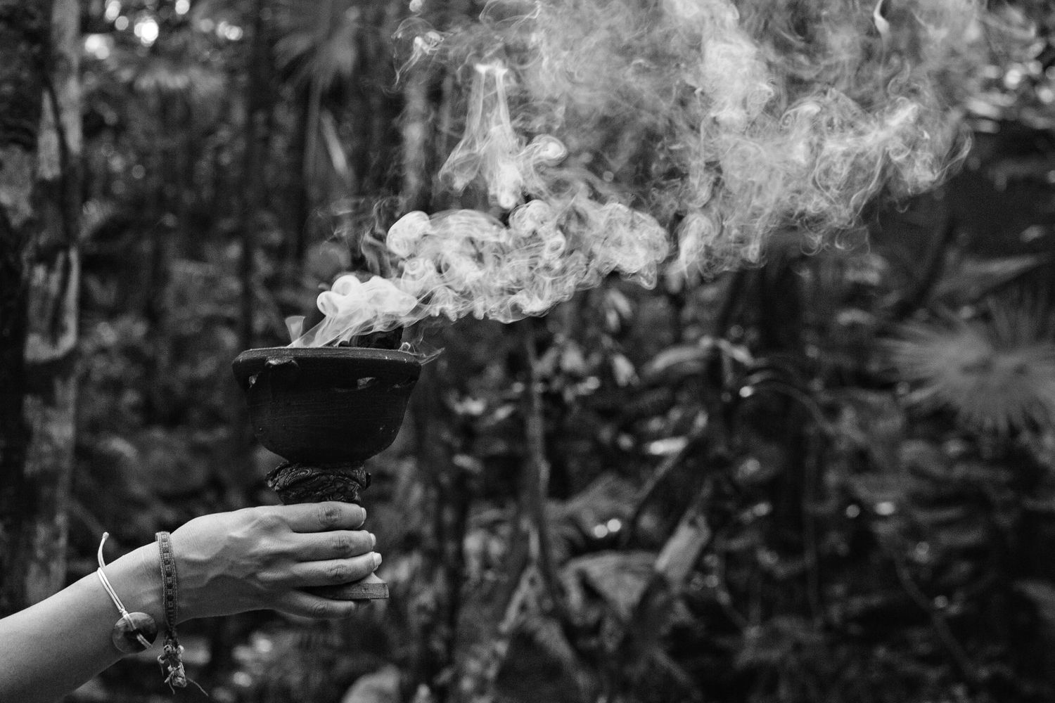 Black and white photograph of smoke rising in a soft swirl against a dark background creating an ethereal pattern.