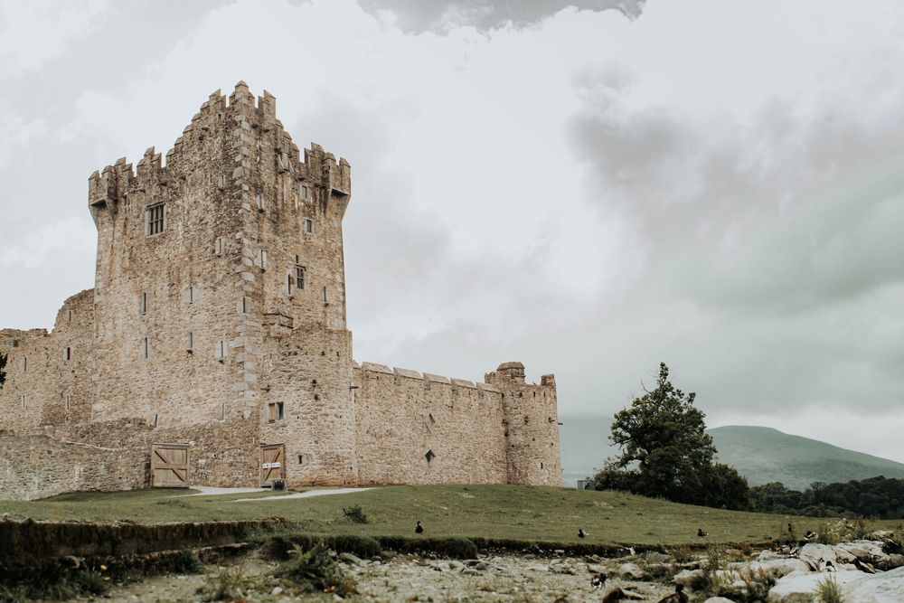Historic Ross Castle stone fortress stands against cloudy sky in Killarney National Park, Ireland.